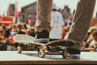person steps on a skateboard in front of a crowd. they’re probably going to fall down a steep slope.