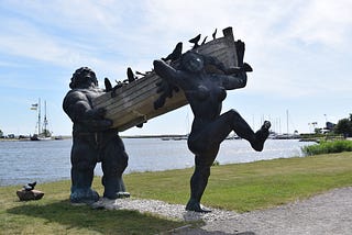 statues of giants carrying a boat ashore