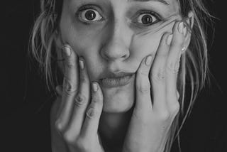 Young lady with both hands to her face looking confused and anxious