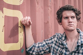 A handsome man standing in front of a shipping container