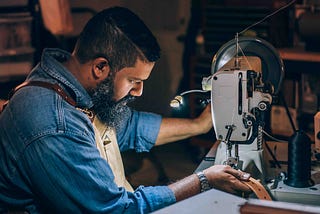 Photo of a person using a sewing machine to stitch a belt. Alt text to show the importance of using alt text.