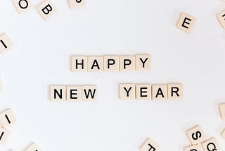 A white surface on which scrabble tiles have been arranged to spell out Happy New Year.