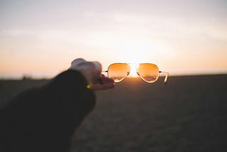 Holding a pair of anti-reflective aviator glasses in the sun