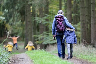 an older woman walking in the woods with her grandchildren