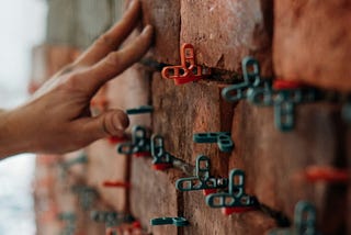 A close image of a hand in the process of building a brick foundation.