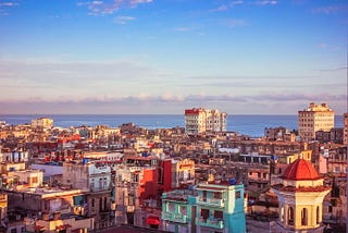 Old Havana morning of buildings and ruins bathed in pastel colors of green, yellow, red and blues. Caribbean sea is behind