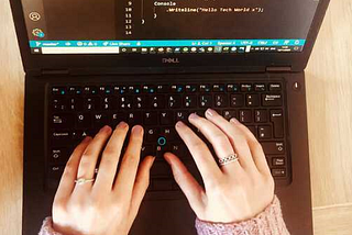 Feminine hands on keyboard with code on screen