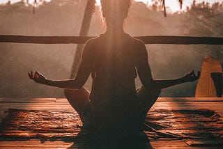 A woman sitting in meditation at sunrise.