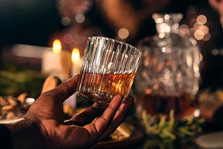 Glass of whiskey held up in evening light.