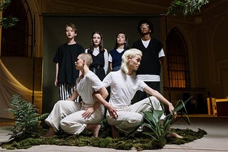 Conceptual photo of dancers clothed in white with people clothed in black behind them.
