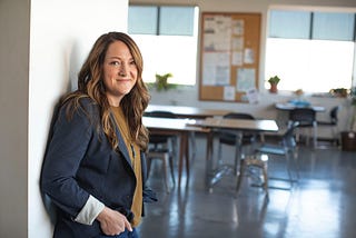 Smiling teacher standing in front of an empty classroom.