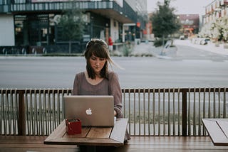 woman sitting outside looking at her laptop