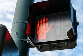 A crosswalk sign showing a red hand for “stop.”