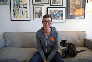 An image of Debra Cleaver sitting on a couch next to a cat.