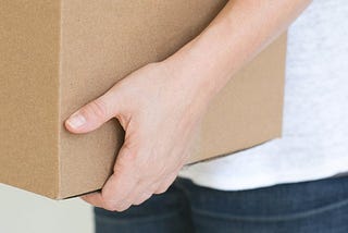 A person carries a large cardboard box