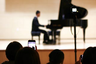A person plays a grand piano on a stage.