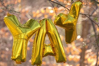 Three gold balloons spelling “YAY”