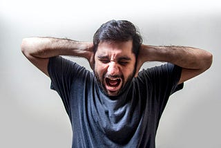an man screaming with his hands over his ears