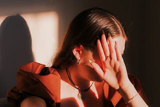 A woman with her hand up hiding her face in distress.