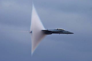 Super sonic plane, breaking the sound barrier, with the distinctive white cloud in the tail of the aircraft that happens when at that high speed.