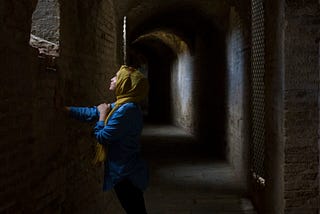 dark hallway with a beautiful woman leaning into the sunlight