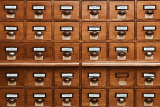 an ancient file cabinet with many labeled drawers.