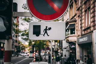 Photo of an illustrated sign of a man leaving a delivery truck with a package.