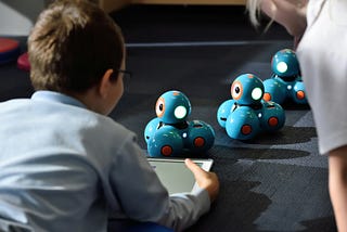 A kid controlling robots with a tablet of some sort.