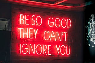 A red neon sign that says “Be so good they can’t ignore you”