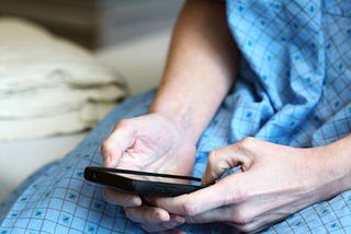 photo of person in hospital gown looking at their phone