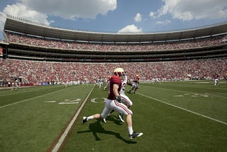 A fotball receiver tries to outrace opponent down the sidelines during a football game.