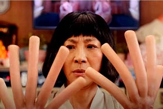 Image from the film Everything Everywhere All at Once where Michelle Yeoh’s hands have become hot dogs