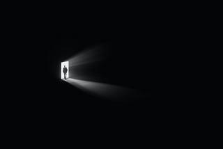 a man entering the dark room and shedding the light from the other room