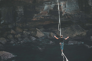 Climber on a rope balancing as he walks over a river