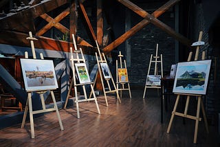 six paintings displayed on easels
