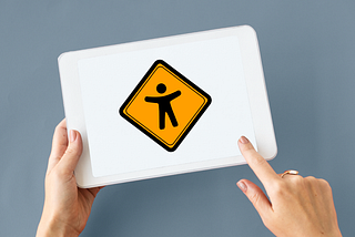 Two hands holding a tablet, the tablet shows a big icon with a stick figure symbolizing digital accessibility