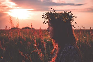 Lone girl wearing a flower crown in a field of flowers