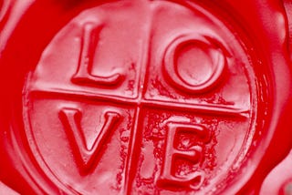 A waxy red circle separated into four, with the letters L, O, V, and E in each quarter