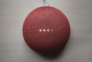 An Alexa-style digital device with three red dots lit up, as it prepares to communicate an answer.