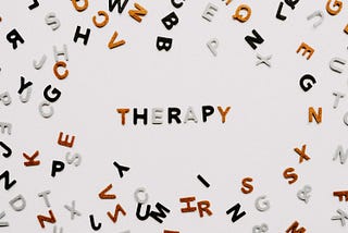 different letters of the alphabet scattered with the letters spelling therapy in the middle