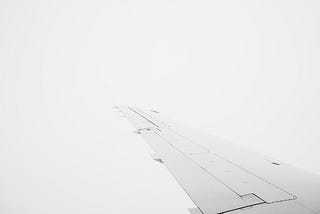 A white image, seemingly blank but there is actually a plane’s wing on it.