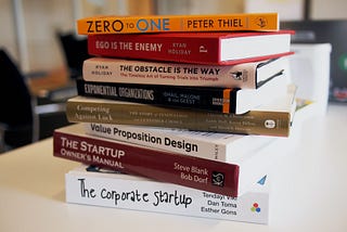 Image shows 8 business self-help books piled on top of each other