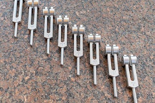 8 Tuning forks sloped down diagonally, left to right.