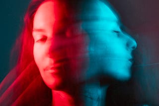 Two blurred images of the same face turning, in red and blue