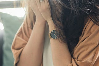 Brunette female with hands covering face.