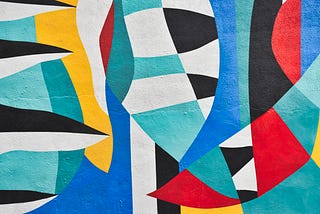 A colorful abstract design painted on a wall, with blue, turqouise, red, yellow and black & white shapes.