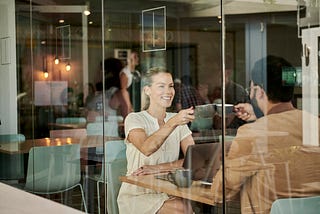 Smiling woman sitting in cafe with man and celebrating moment.