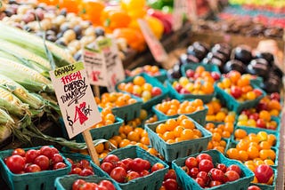 Fresh cherry tomatoes, corn, and other vegetables at a farmers market