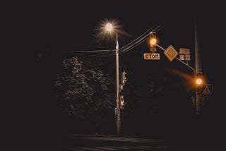 A photo of a brightly lit street light and traffic lights at night.