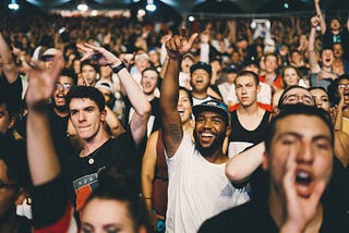 Groups of excited young people with raised hands inside a stadium-like area